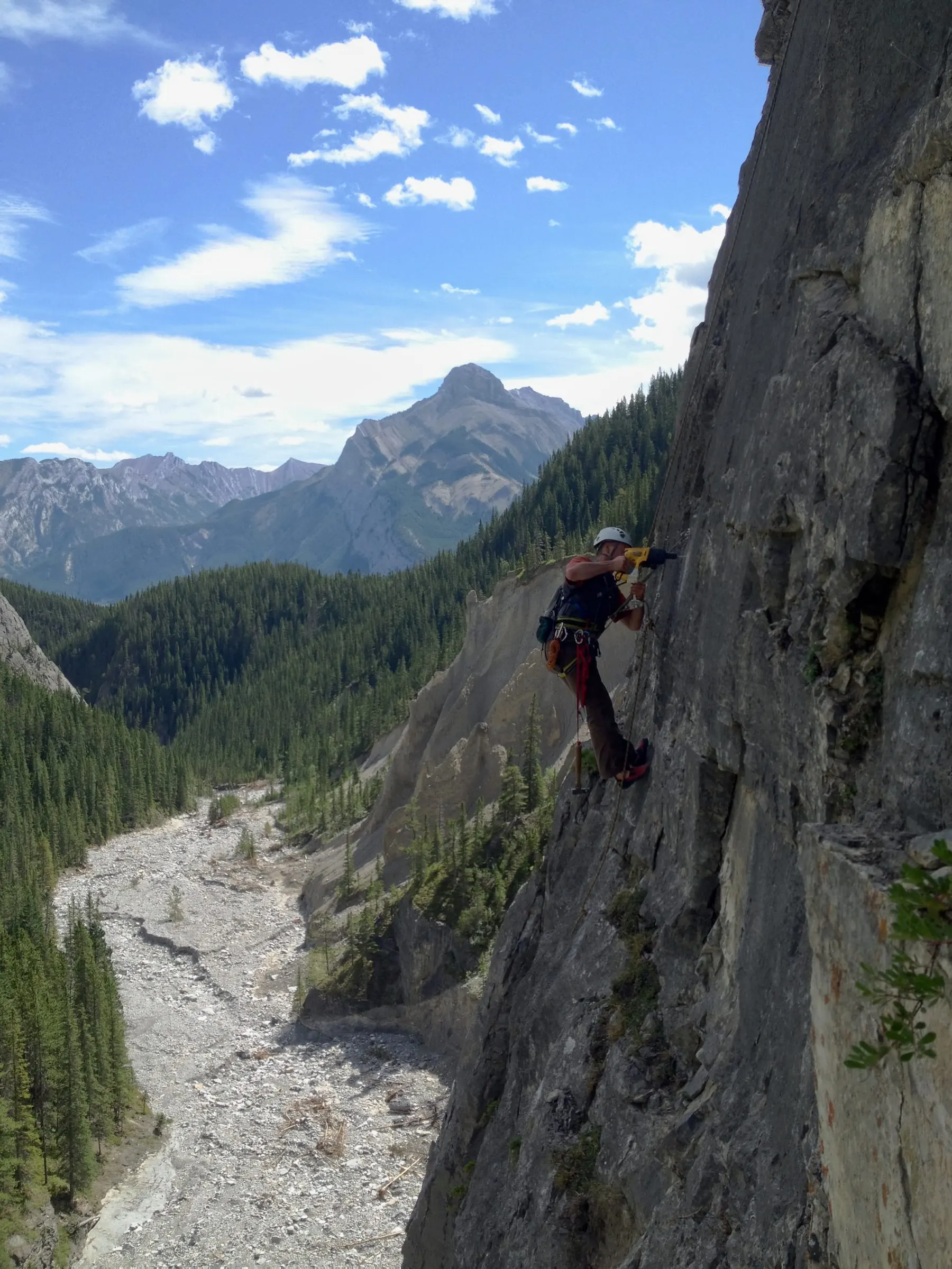 A route developer drills into a limestone wall high above the floor of Grotto Canyon